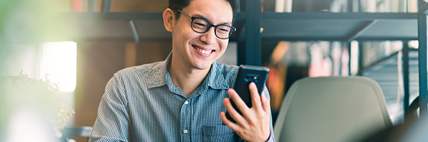 Man glimlacht terwijl hij een Android toestel vasthoudt en bekijkt.